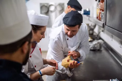 Partenariat avec la Fondation Club Med. Jeunes du dispositif "SKOLA Restauration / La Salle à manger" accueillis au sein du Resort Club Med de Grand Massif Samoëns Morillon en Haute-Savoie afin de découvrir le fonctionnement de ses cuisines et de son service. Ici, dans les cuisines avec un cuisinier du Club Med.