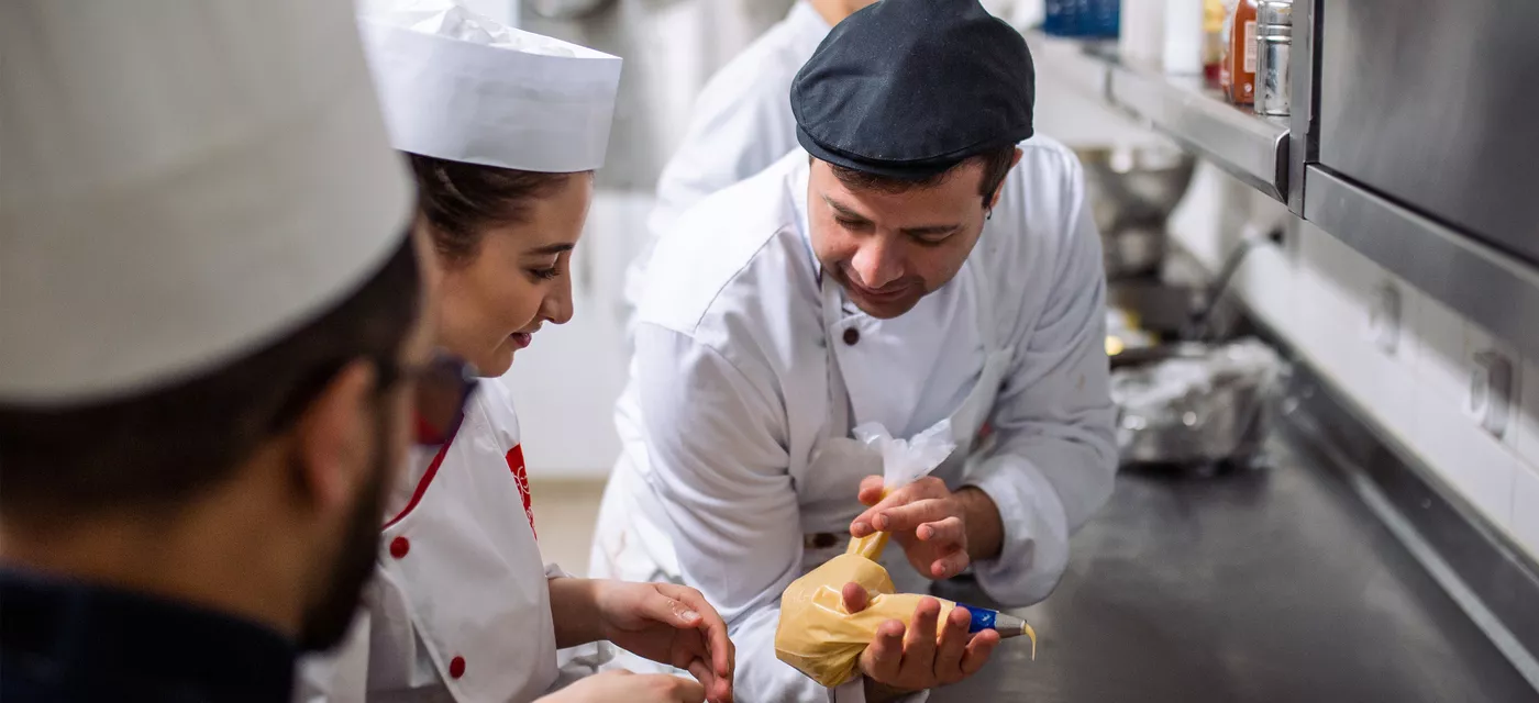 Partenariat avec la Fondation Club Med. Jeunes du dispositif "SKOLA Restauration / La Salle à manger" accueillis au sein du Resort Club Med de Grand Massif Samoëns Morillon en Haute-Savoie afin de découvrir le fonctionnement de ses cuisines et de son service. Ici, dans les cuisines avec un cuisinier du Club Med.